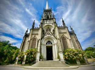 white and brown concrete church under white clouds and blue sky during daytime