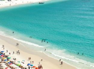 a group of people standing on top of a sandy beach